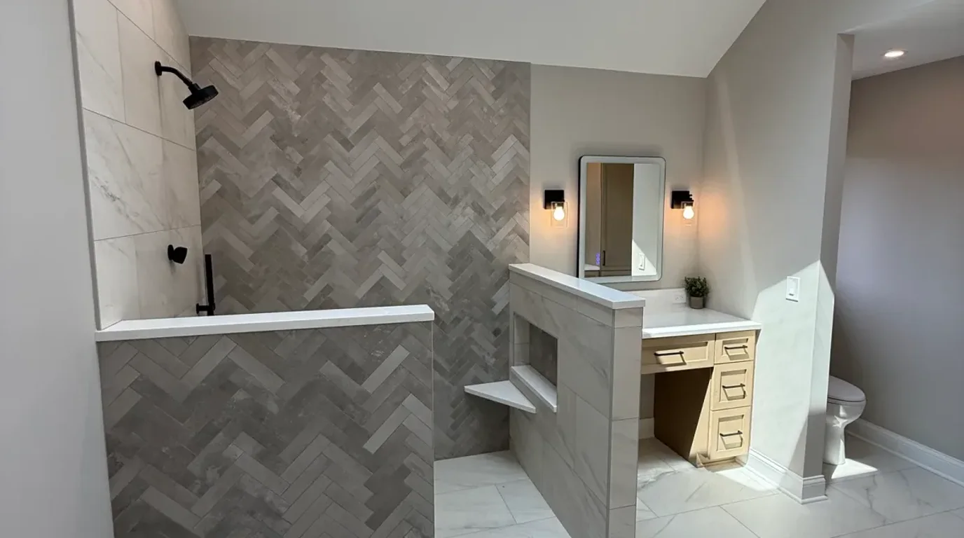 Bathroom after photo, Mokena IL - open walk-in shower with a full-height herringbone accent wall and knee walls with stone-look caps, with a seated makeup station beyond
