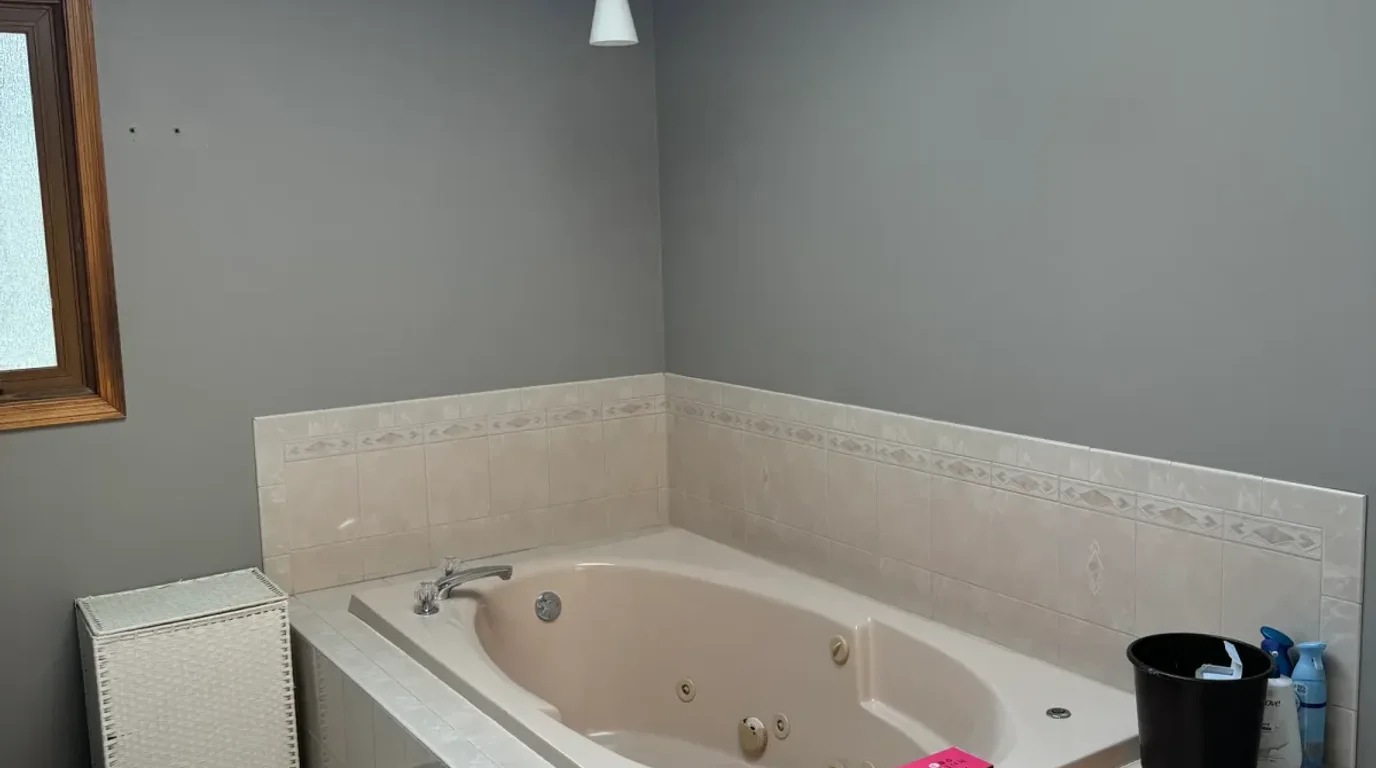 Before: a 1990s drop-in jetted tub set into a raised cultured-marble deck with grey walls and oak trim in a Mokena, IL bathroom