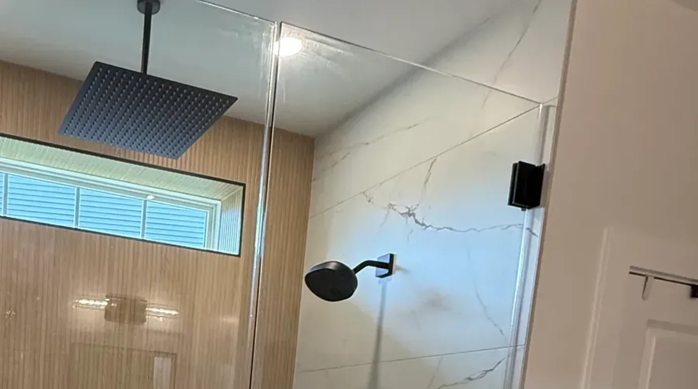 Shower after photo, Shorewood IL - frameless glass shower in warm reeded wood-look tile and marble-look porcelain, with a ceiling rain head and matte black fittings
