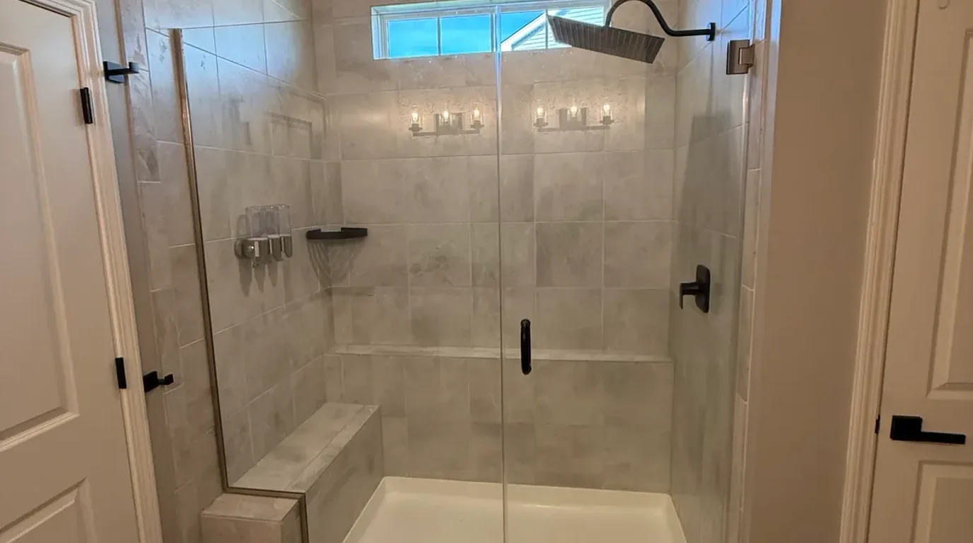 Shower before photo, Shorewood IL - builder-grade marble-look shower with a built-in bench behind framed glass