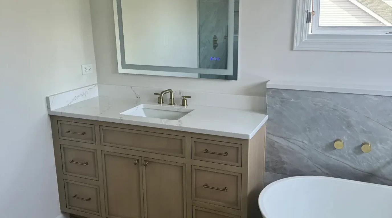 After: a light-oak vanity with a white quartz top with grey veining, rectangular undermount basin, brass tapware and a backlit mirror, Shorewood IL bath remodel