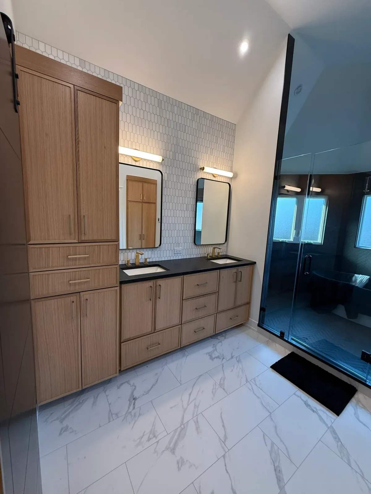 White oak double vanity with a black stone top, black-framed arched mirrors, a white zellige tile wall and marble-look floor tile - Mokena IL