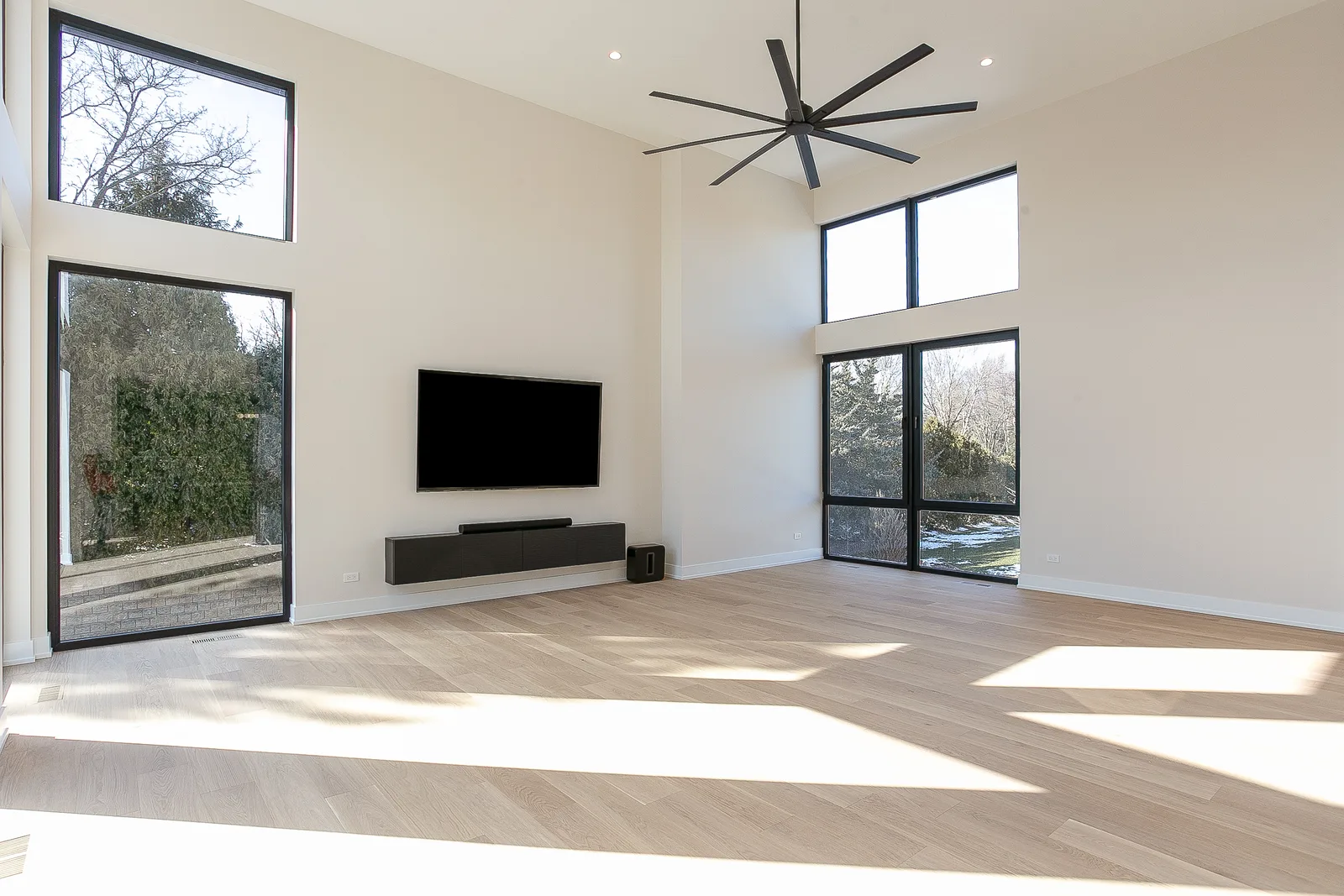 Vaulted great room with floor-to-ceiling black-framed windows and wide-plank oak floors, custom home in Lemont, IL by Luxe Development