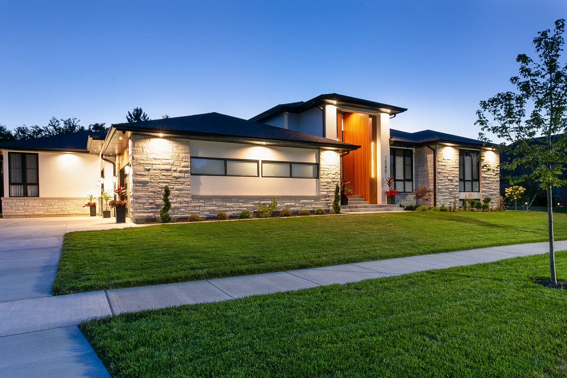 Custom home in Lemont, IL - modern limestone, wood and glass exterior at dusk by Luxe Development