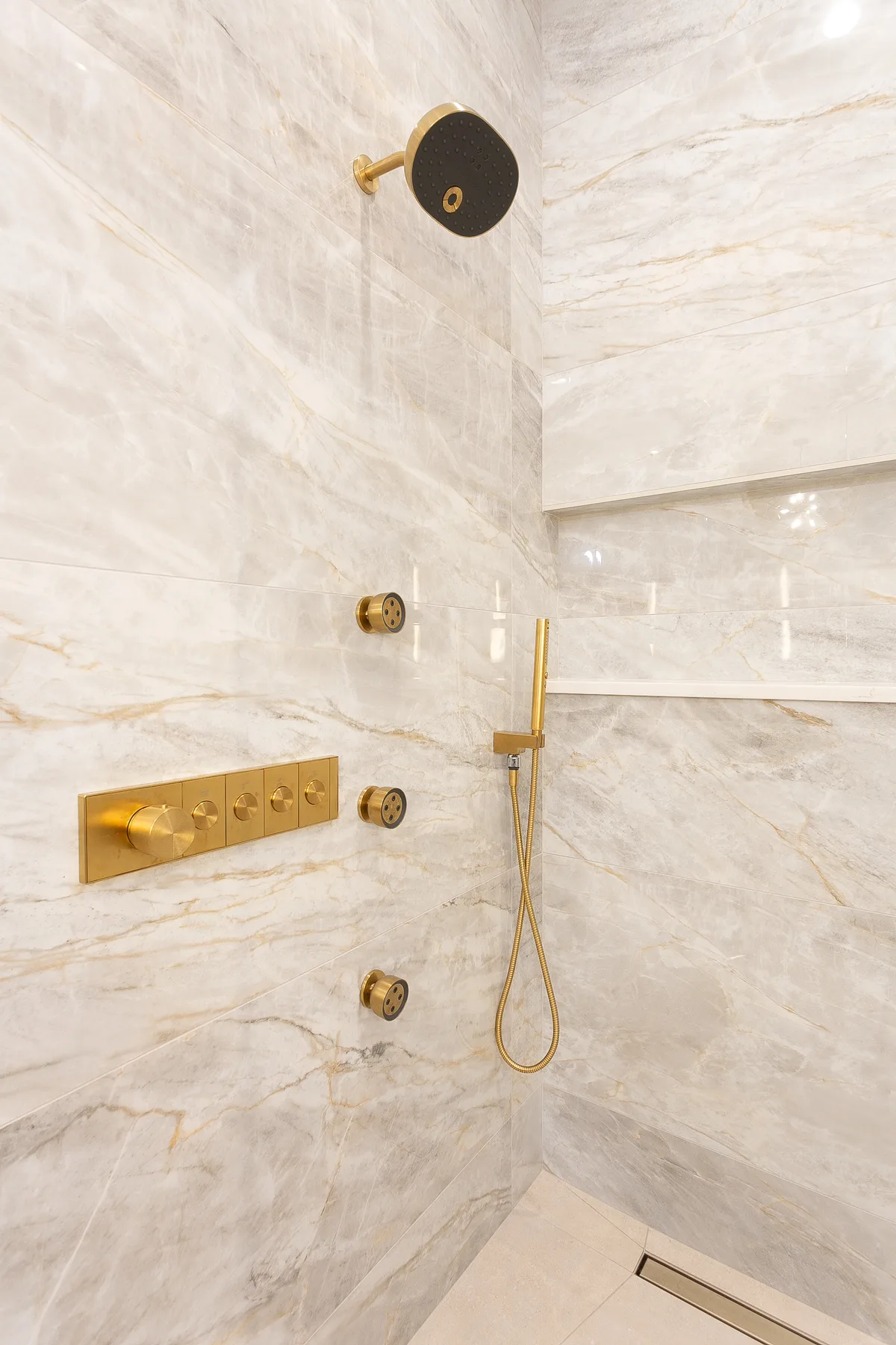Walk-in shower wrapped in veined stone with brass fixtures - custom home, Lemont IL