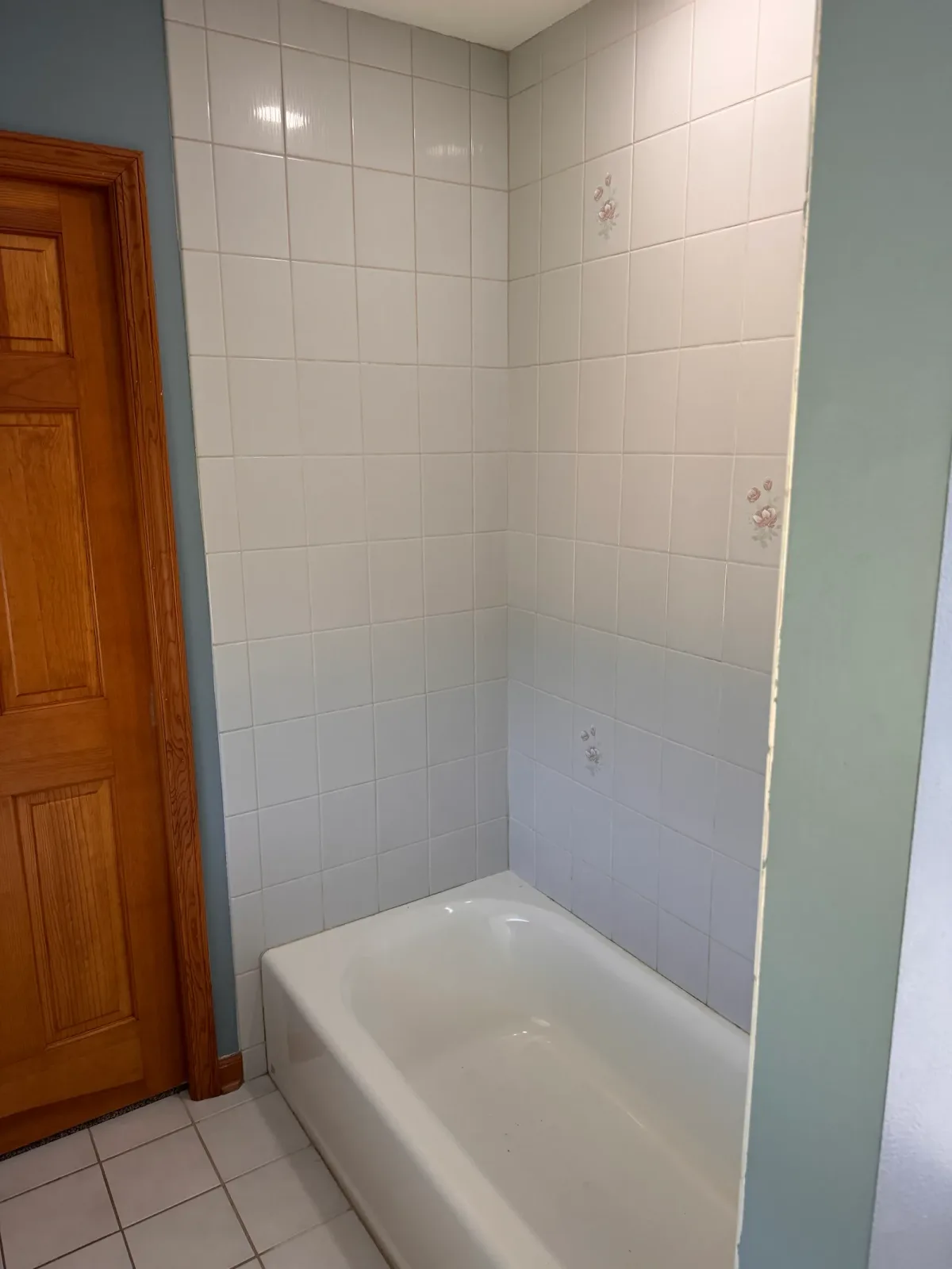 Guest bathroom before photo, Shorewood IL - alcove bathtub in white square wall tile with painted rose accent tiles, beside an oak door and oak casing