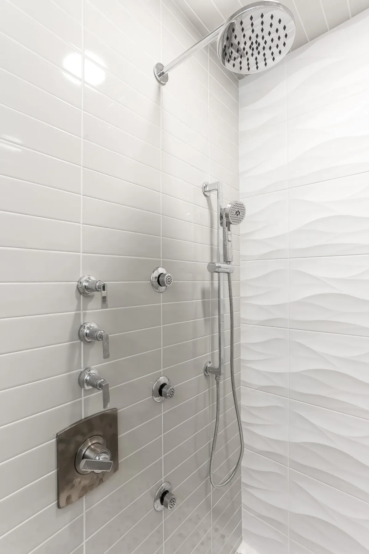 Thermostatic valves and body sprays set into the shower wall, condo renovation in Chicago, IL