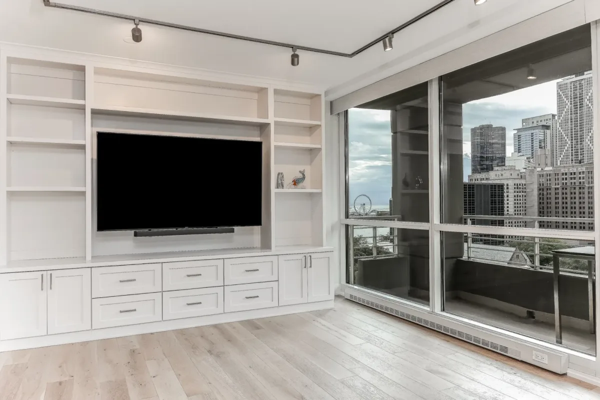 Living room built-in millwork running to a full-height glass wall, condo renovation in Chicago, IL