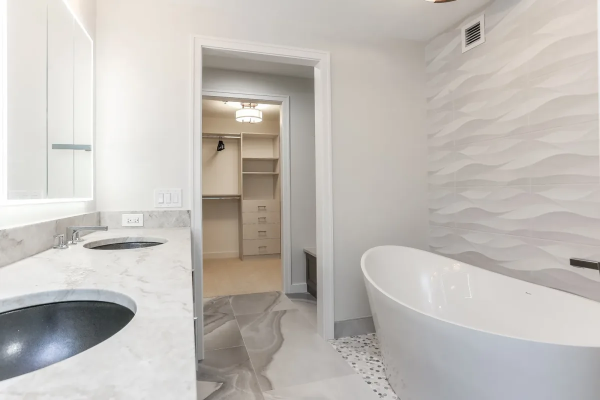 Freestanding soaking tub with the fitted walk-in closet beyond, condo renovation in Chicago, IL
