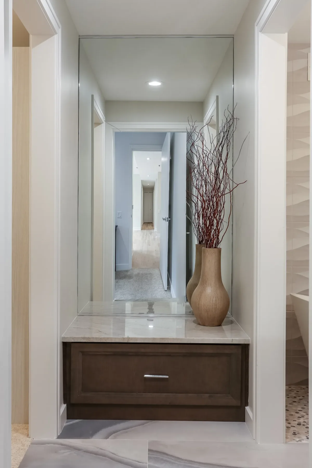 Floating stained cabinet with a stone top and full-height mirror set into the hall of a Chicago condo renovation