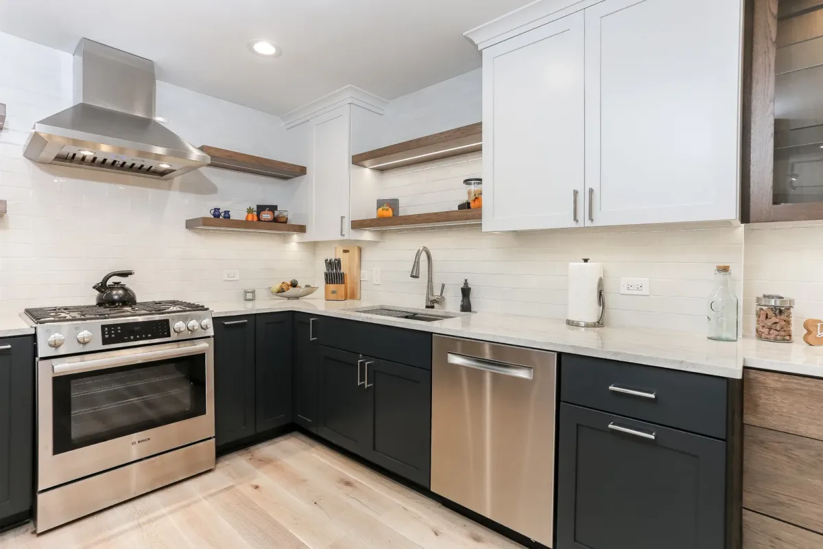 Stainless chimney hood over the range with lit floating shelves and full-height glossy tile in a Chicago condo kitchen renovation
