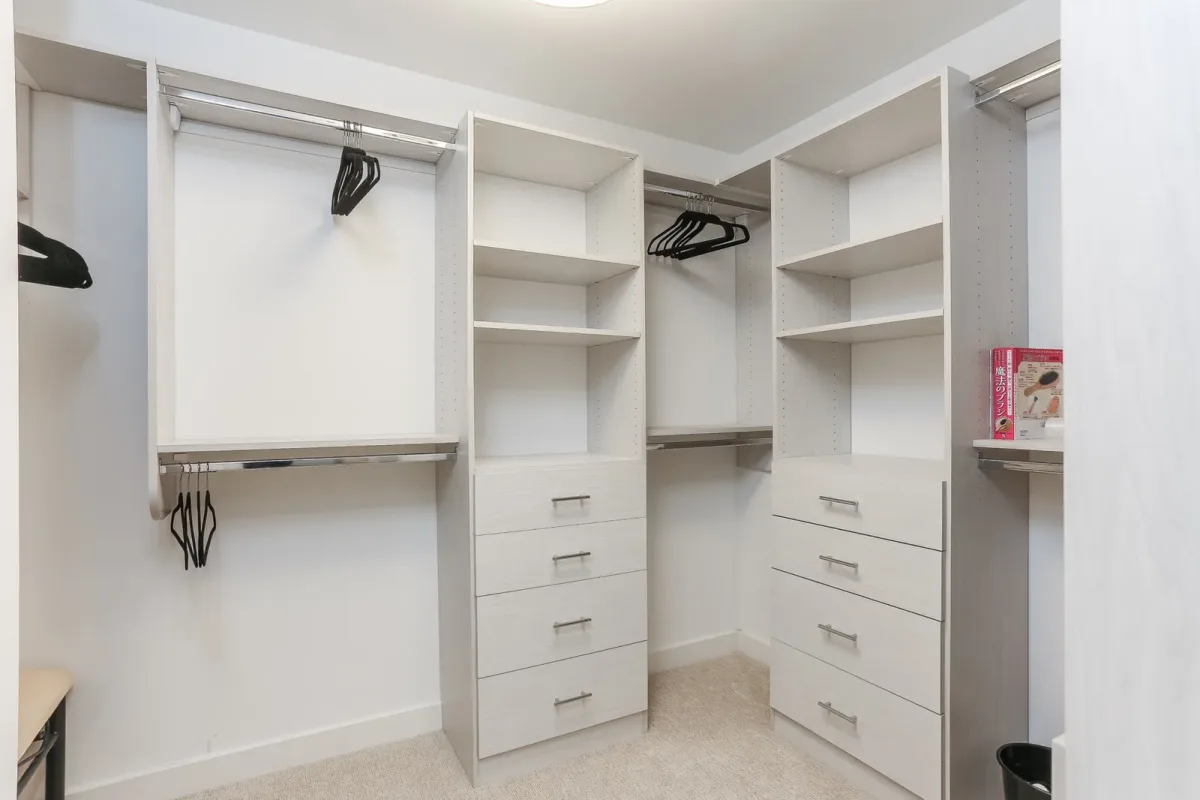 Fitted walk-in closet system in light woodgrain panel with chrome hanging rods in a Chicago condo renovation