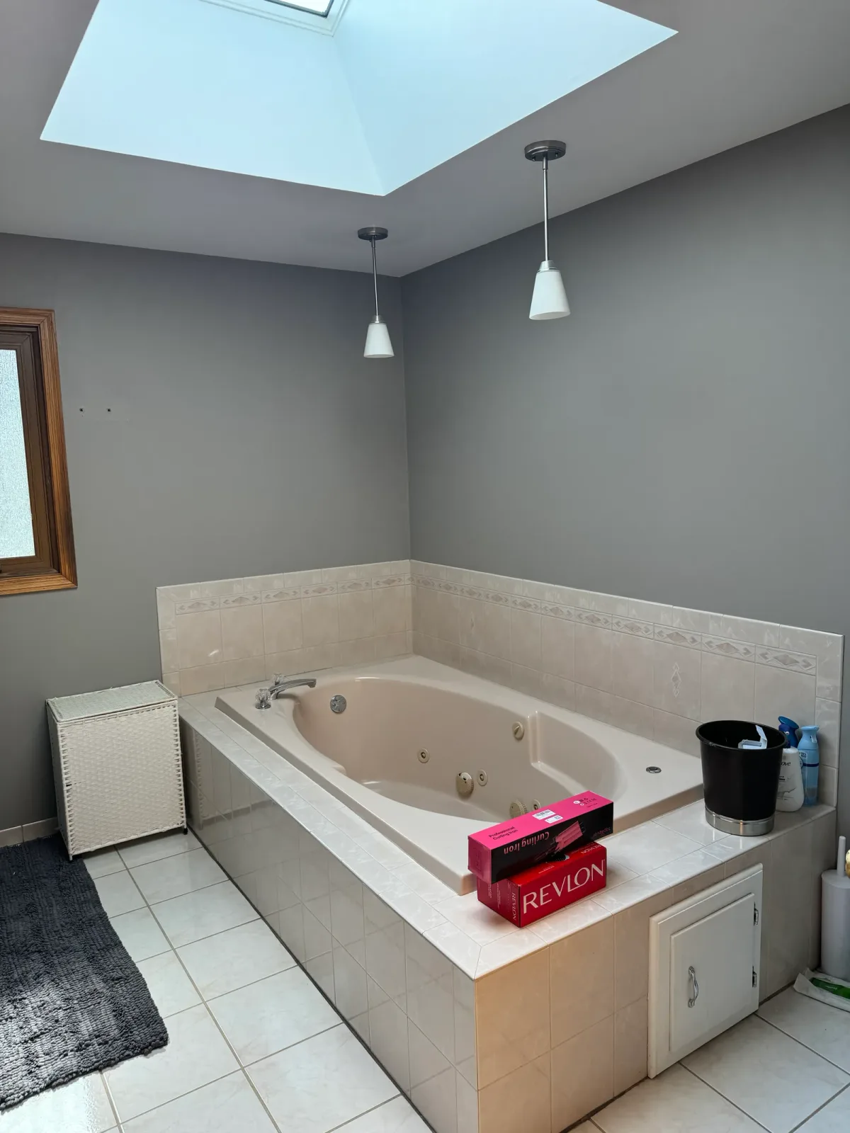 Bathroom remodel before photo, Mokena IL - 1990s drop-in jetted tub set into a raised cultured-marble deck under a skylight, with grey walls and oak trim