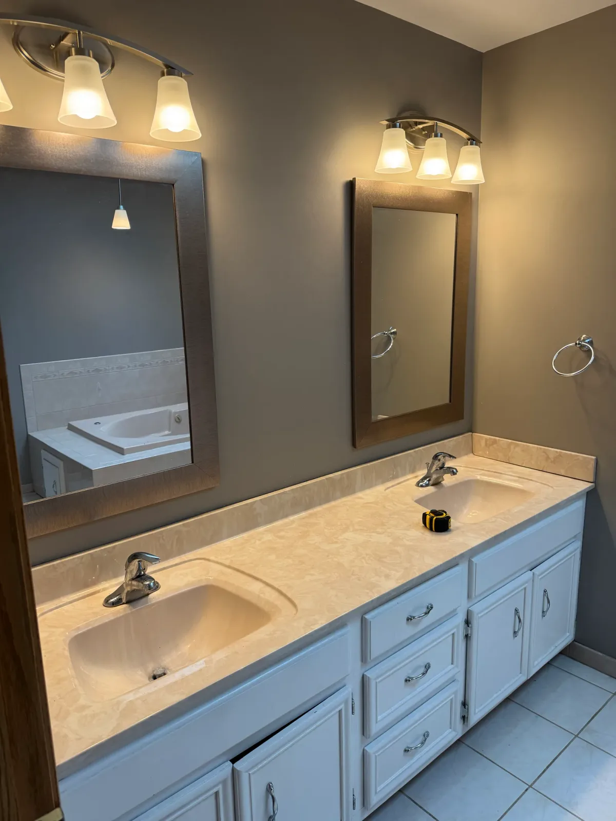 Bathroom remodel before photo, Mokena IL - oak double vanity with a cultured-marble integrated sink top, a frameless plate mirror and a chrome light bar