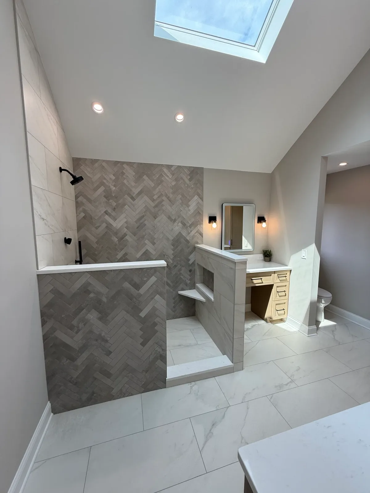 Bathroom remodel after photo by bathroom remodeling contractors in Mokena, IL - open walk-in shower with a full-height herringbone accent wall and stone-look capped knee walls