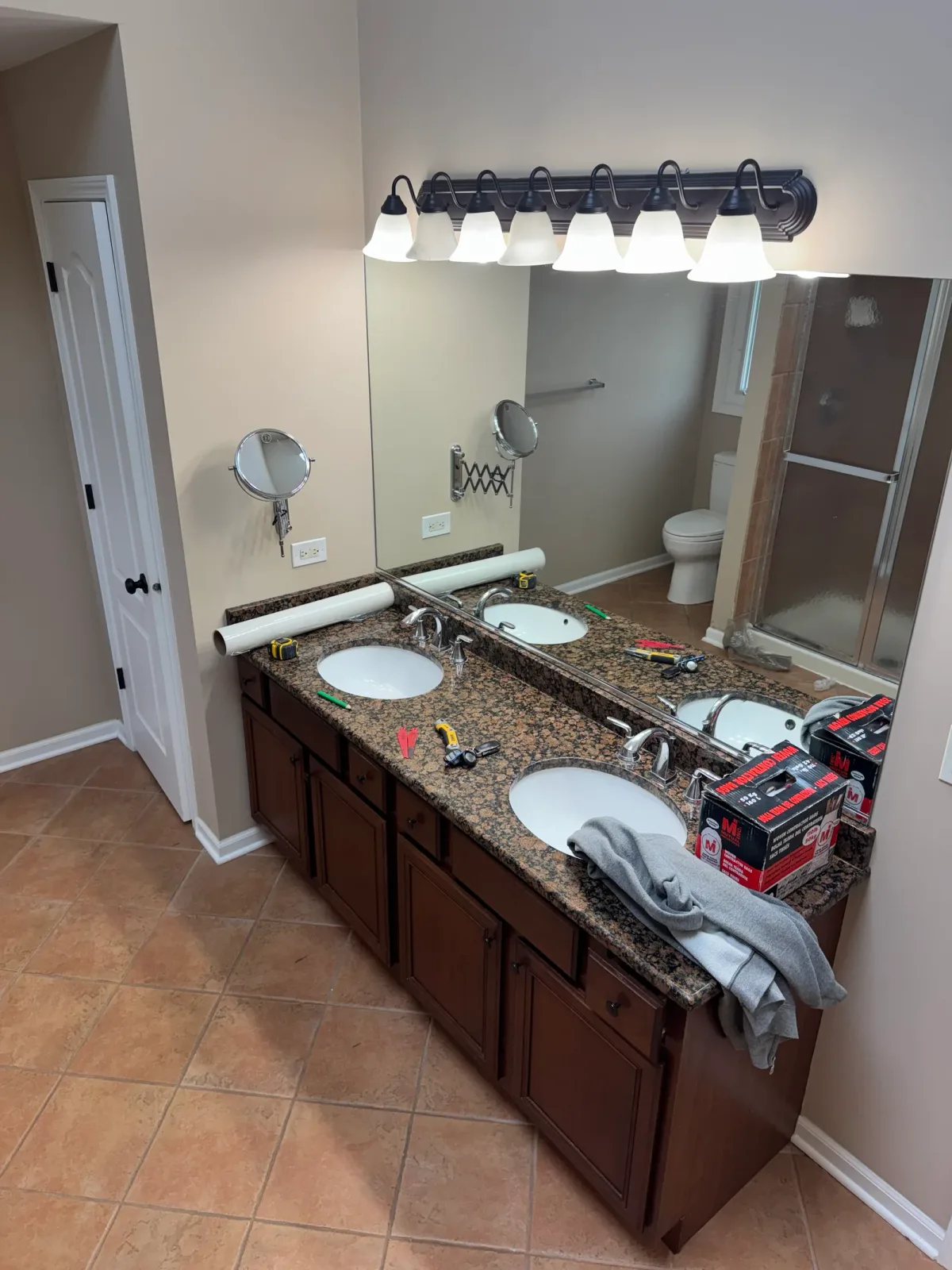 Bathroom remodel before photo, Mokena IL - cherry-stained double vanity with a granite top, oval sinks and a full-width plate mirror