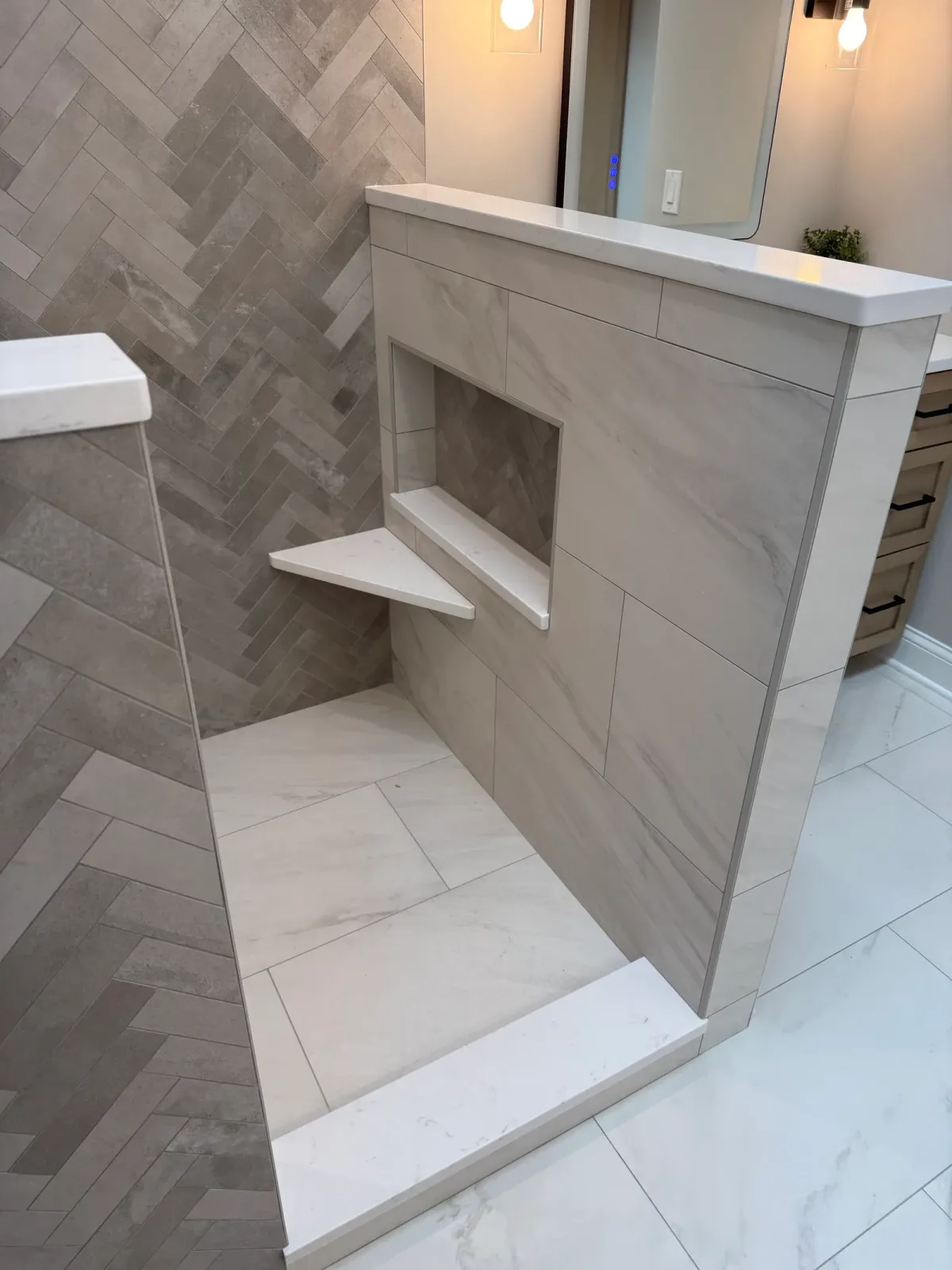 Built-in stone-look corner bench and a recessed niche backed in the herringbone tile - primary bath remodel, Mokena IL