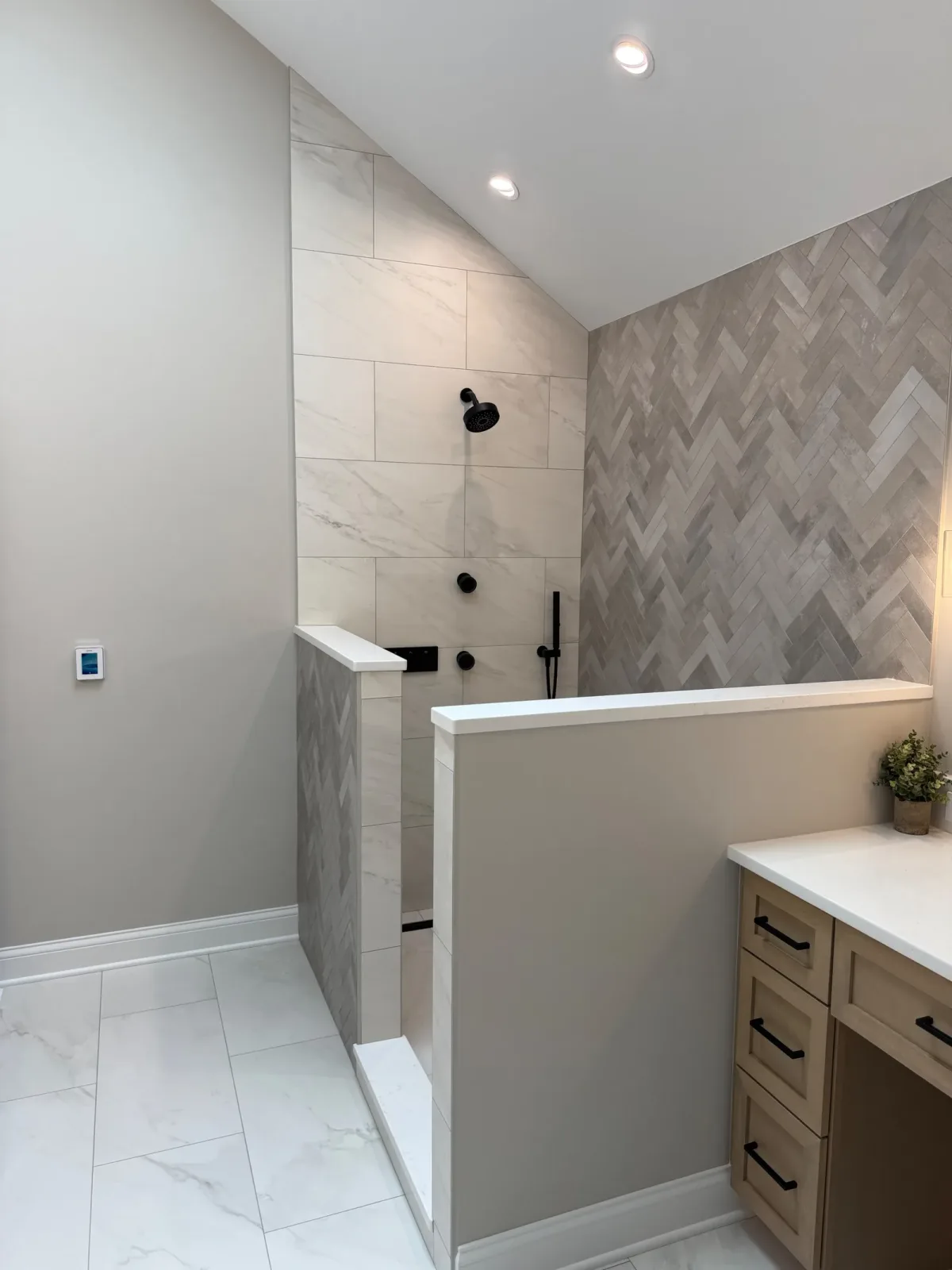 Shower knee wall with a stone-look cap, with the seated makeup station beyond - primary bath remodel, Mokena IL