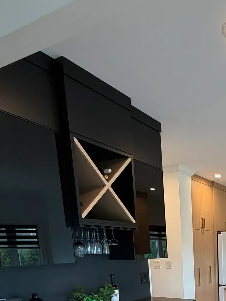 Matte black bar cabinetry with an inset white oak X wine rack and a stemware rail of hanging glasses, beside a window - whole-home renovation, Mokena IL