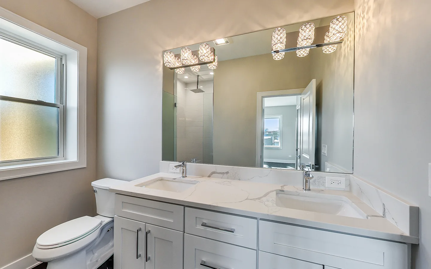 Bathroom double vanity with a stone top and framed mirror by Luxe Development