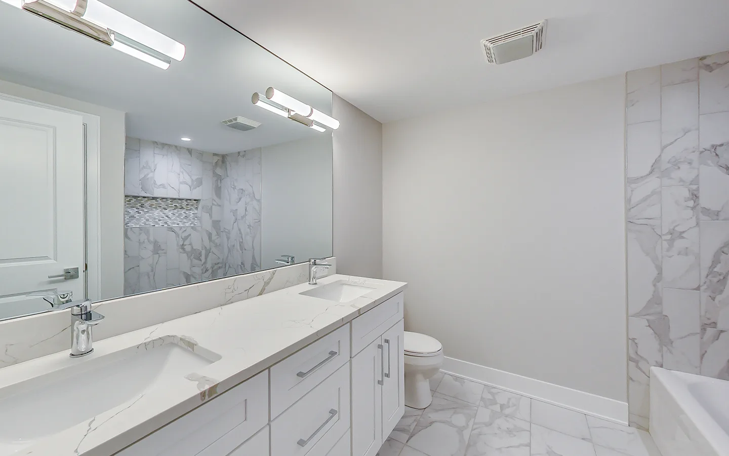 Bathroom with a marble feature wall and quartz double vanity by Luxe Development