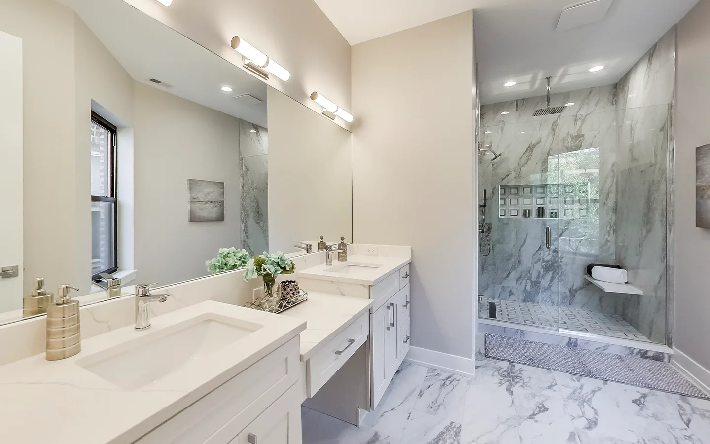 Primary bathroom with a marble walk-in shower and double vanity by Luxe Development