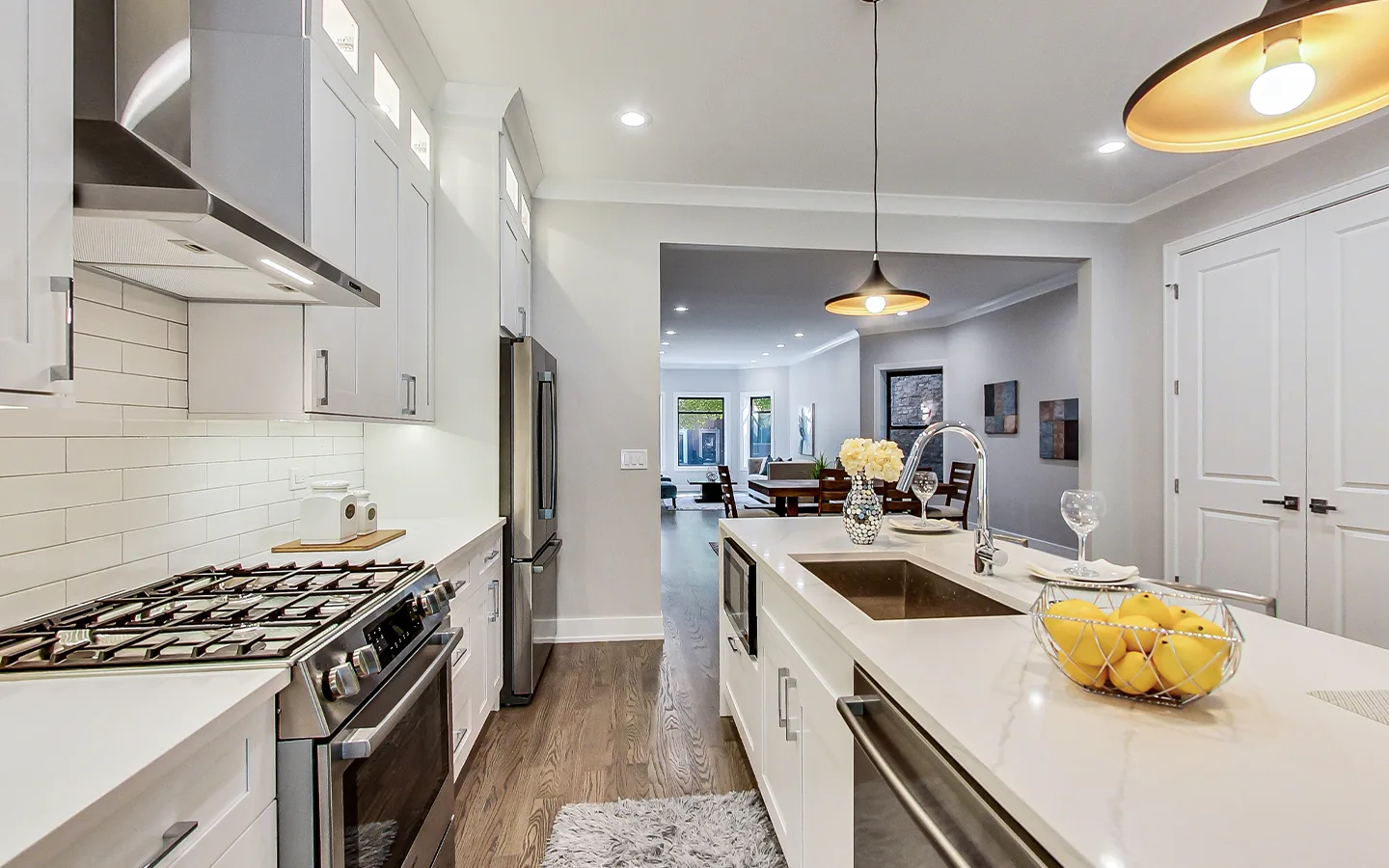 White shaker kitchen with custom cabinetry, a gas range and a quartz island by Luxe Development