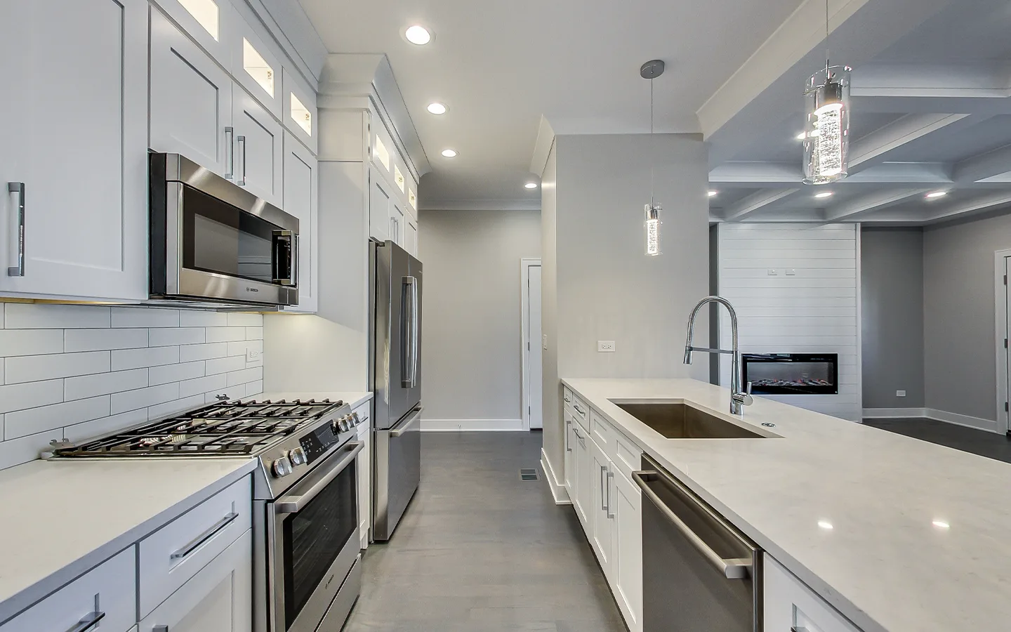 Kitchen with island pendants and layered recessed lighting by Luxe Development